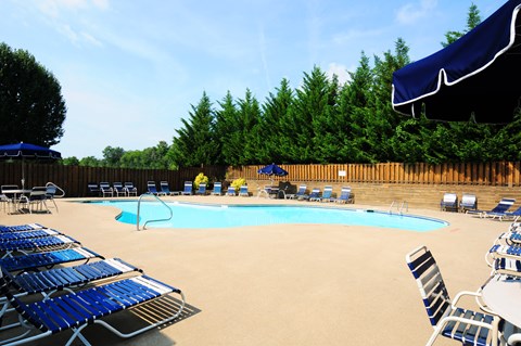 A pool with blue chairs and a blue umbrella.
