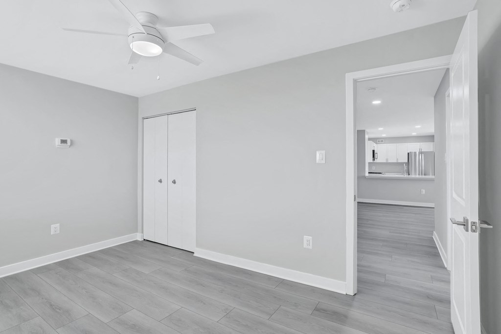 the living room of a new home with white walls and a ceiling fan