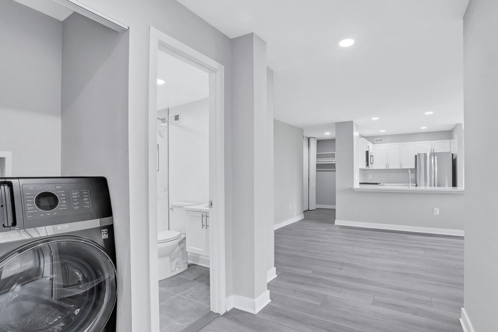 a washer and dryer in a white room with a bathroom and a kitchen