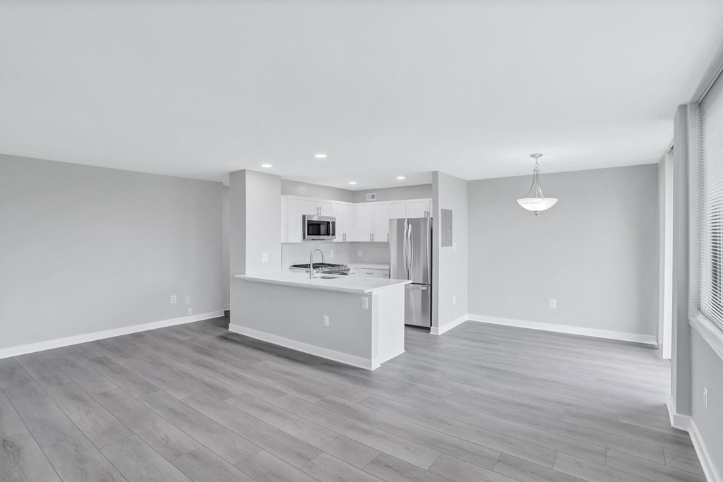 a renovated living room and kitchen with white walls and wood floors