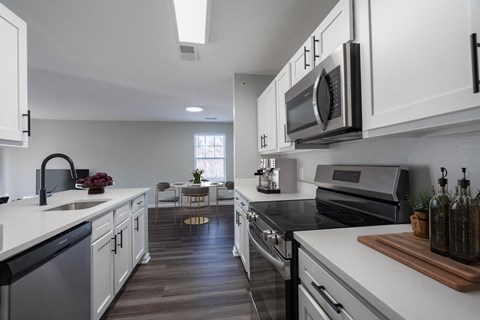 A modern kitchen with white cabinets and black appliances.
