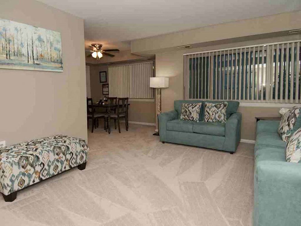 a living room with a couch and a chair and a dining room