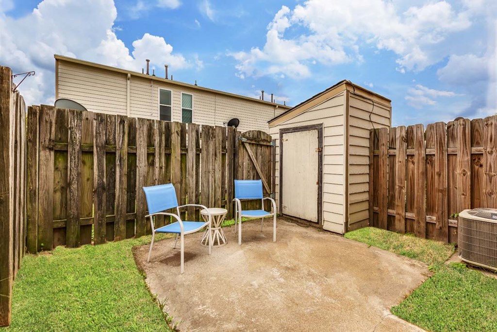 a backyard with a shed and two chairs and a table