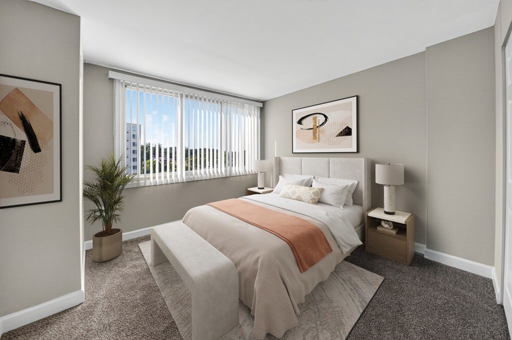 A bedroom with a bed, nightstand, and window.