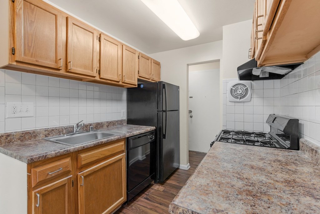 A kitchen with black appliances and wooden cabinets.