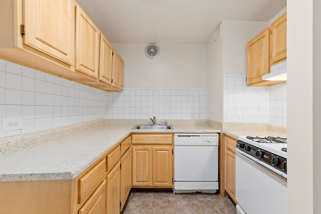 A kitchen with wooden cabinets and a white dishwasher.