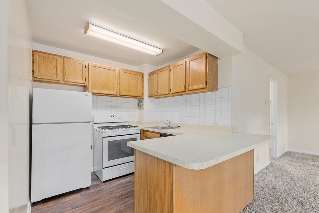 A kitchen with white appliances and wooden cabinets.