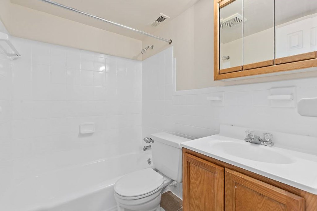 A white bathroom with a toilet, sink, and mirror.