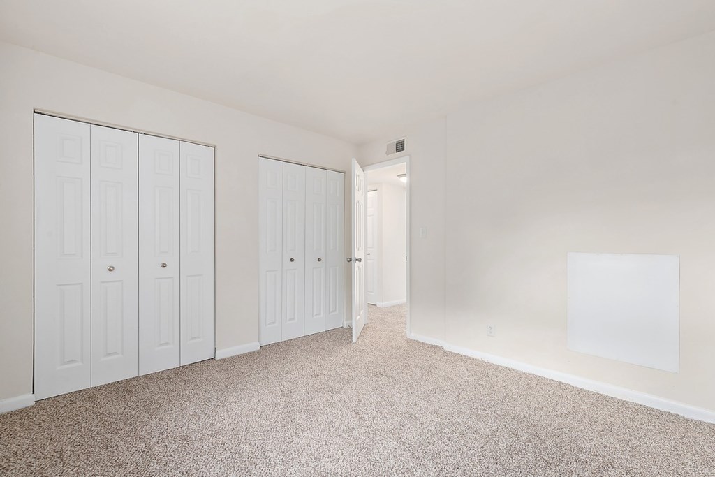 A white room with a carpeted floor and three white doors.