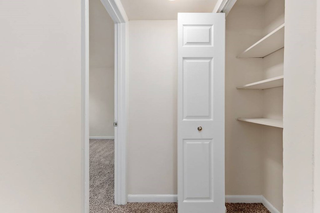 A white door is in a hallway with a carpeted floor.