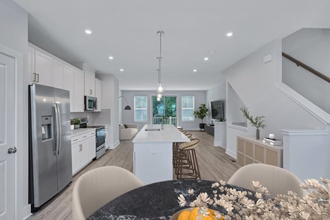 an open kitchen and dining room with white cabinets and stainless steel appliances