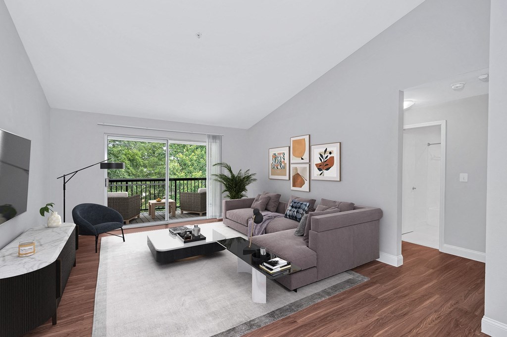 A furnished luxury apartment living room with balcony showing wooded view.