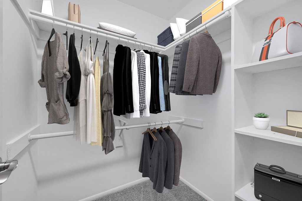 a walk in closet with white shelves and rails and a white rod with clothes hanging from it