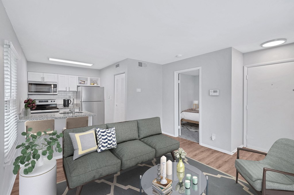 a living area with a couch coffee table and chairs and a kitchen in the background