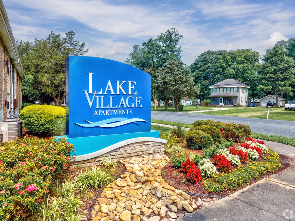 the entrance to lake village apartments sign in front of flowers