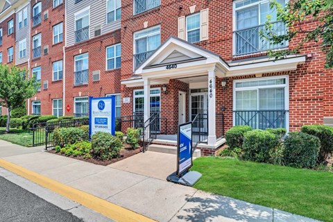 the front entrance of a brick building with a porch and lawn