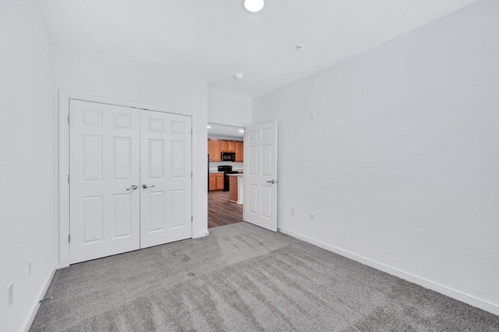 a bedroom with two closets and a door to a kitchen