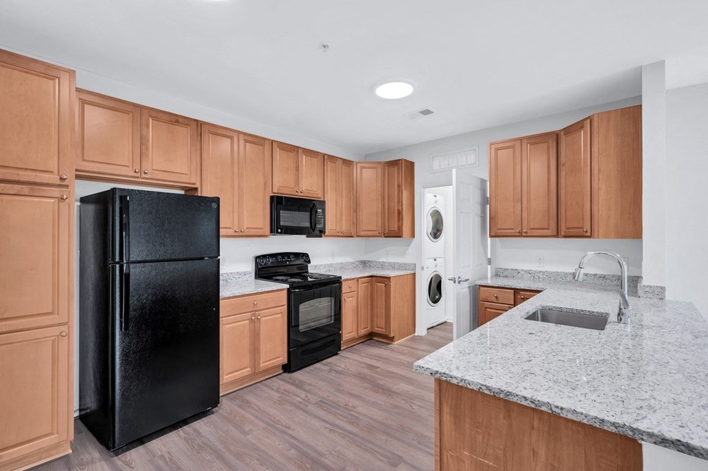 a kitchen with wooden cabinets and a black refrigerator