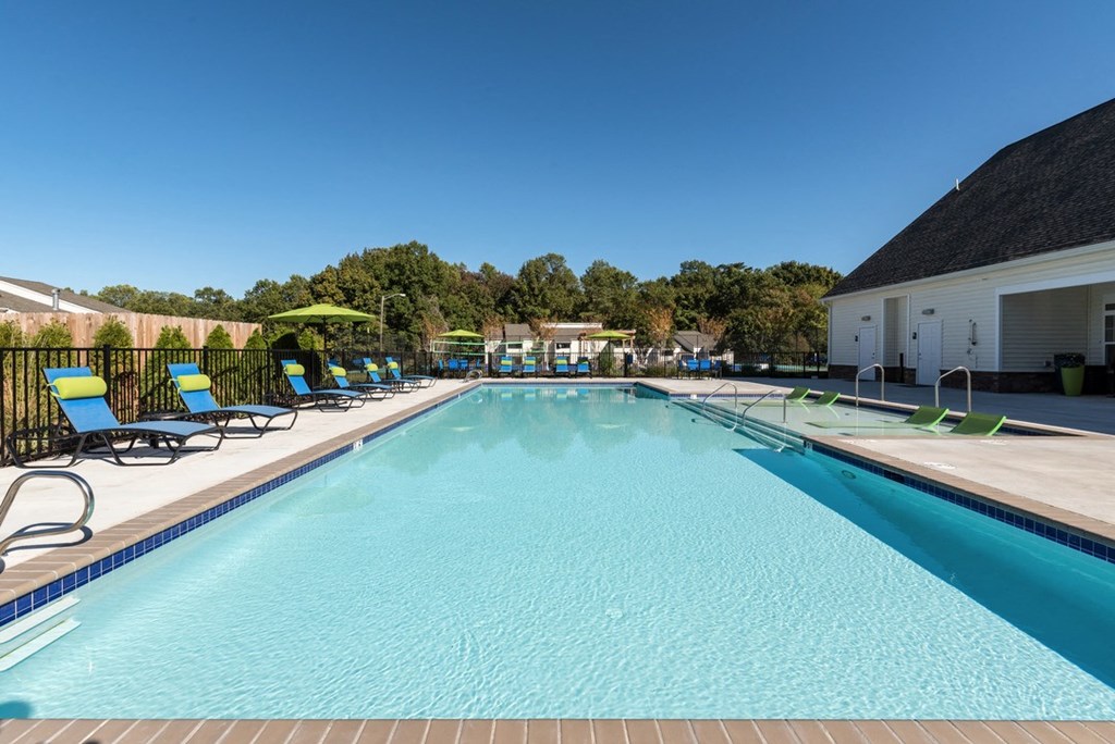 a swimming pool with lounge chairs and umbrellas in front of a building