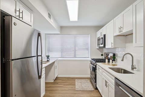 A modern kitchen with a stainless steel refrigerator and white cabinets.