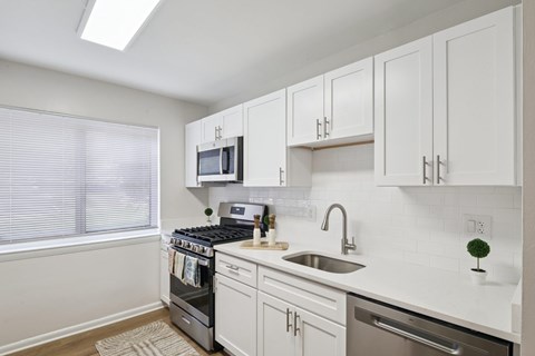 A kitchen with white cabinets and a stove top oven.