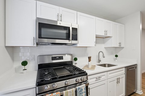 A modern kitchen with white cabinets and a stainless steel stove.