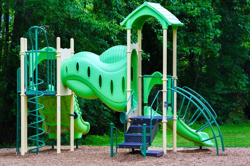a playground with a large green dinosaur