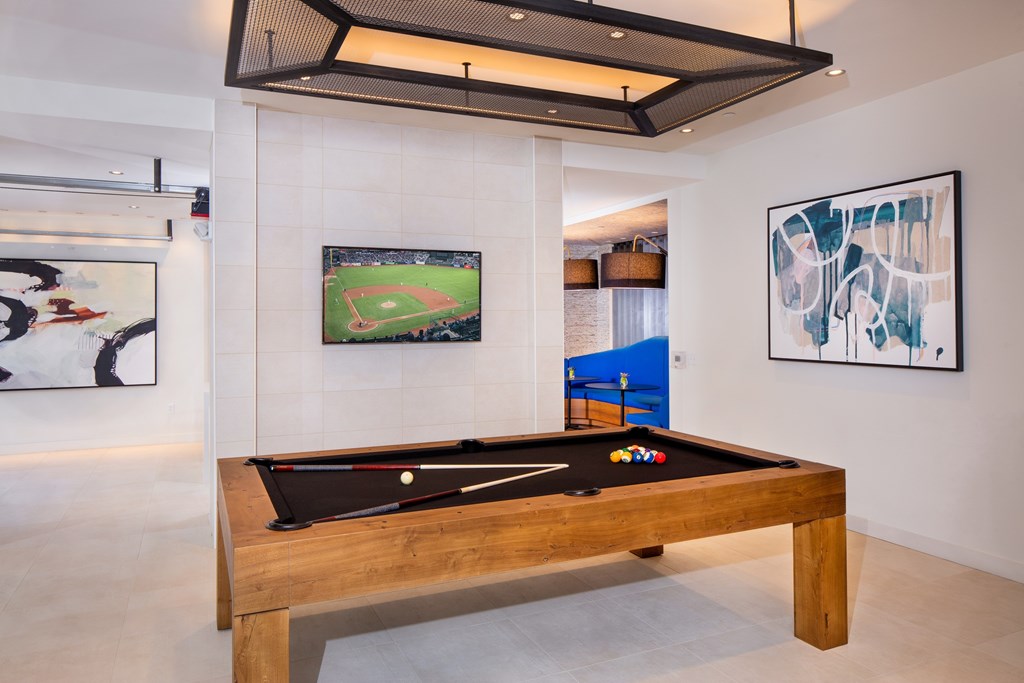 A pool table in a room with a painting of a baseball field on the wall.