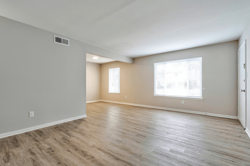 the living room of an empty house with wood floors and a window