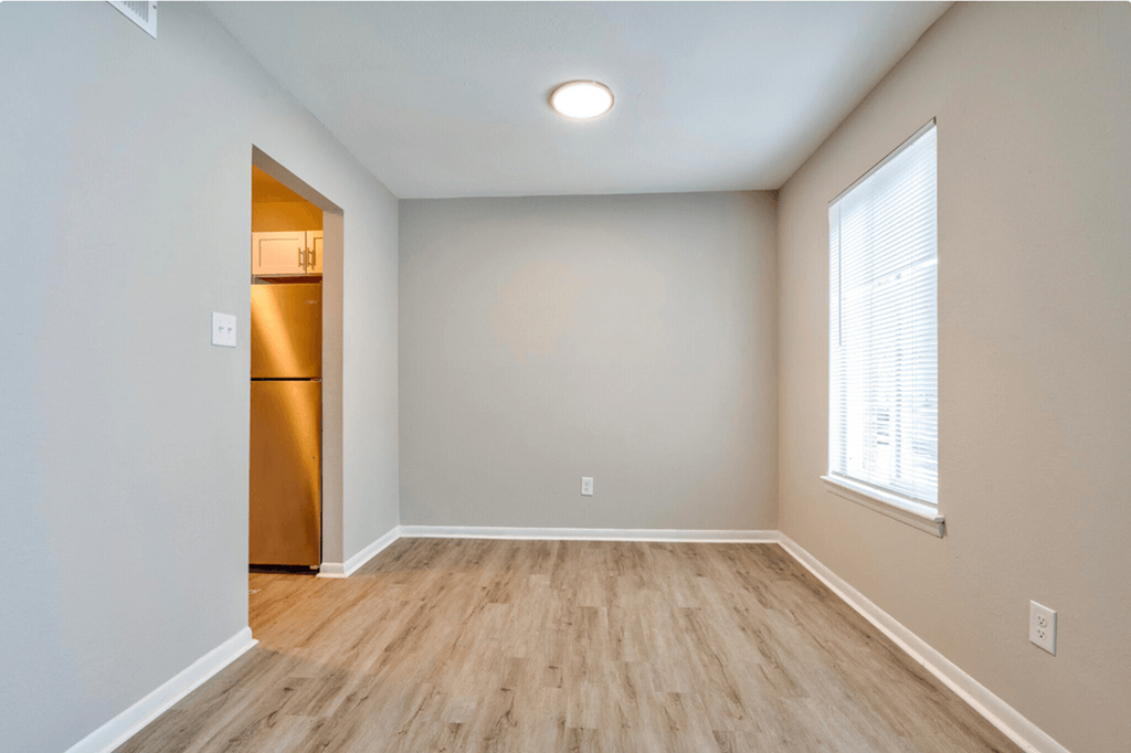 the spacious living room with wood flooring and a large window