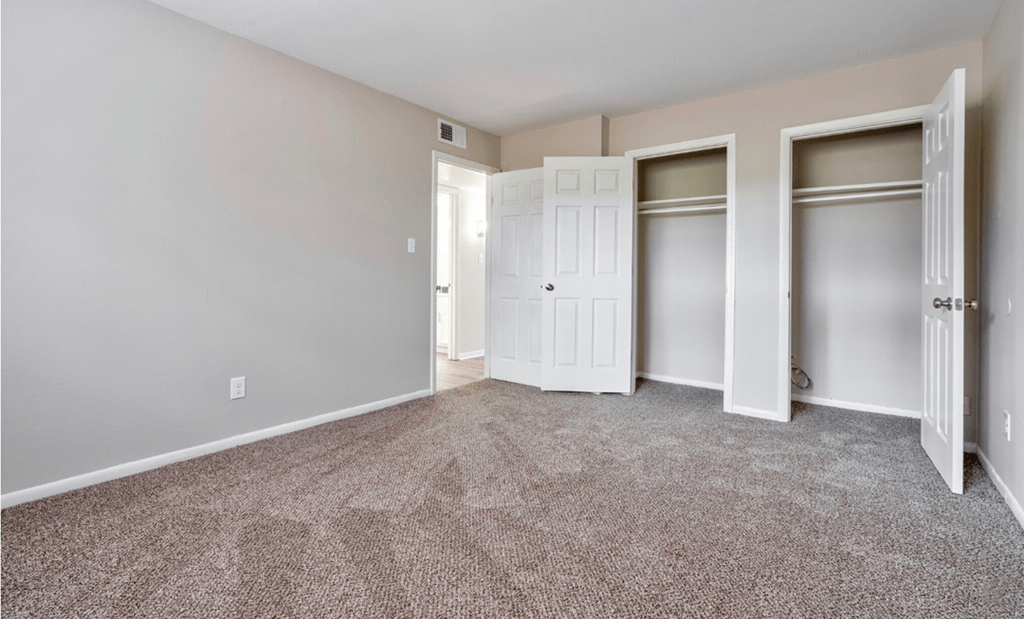 an empty bedroom with three closets and a carpeted floor