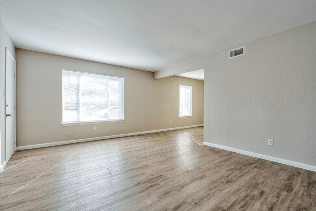 the living room of an empty house with wood floors and a window