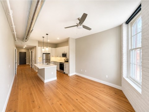 A spacious room with wooden floors and a ceiling fan.
