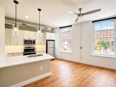 A kitchen with a white counter top and wooden floors.