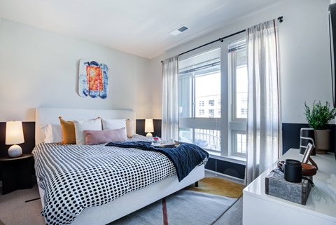 A bedroom with a large bed and a window with curtains.