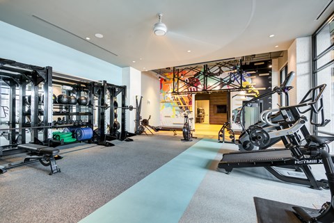 A gym with a variety of equipment including a treadmill, weights, and a bench.