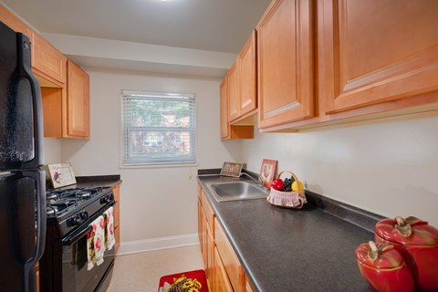 A kitchen with a black fridge and wooden cabinets.
