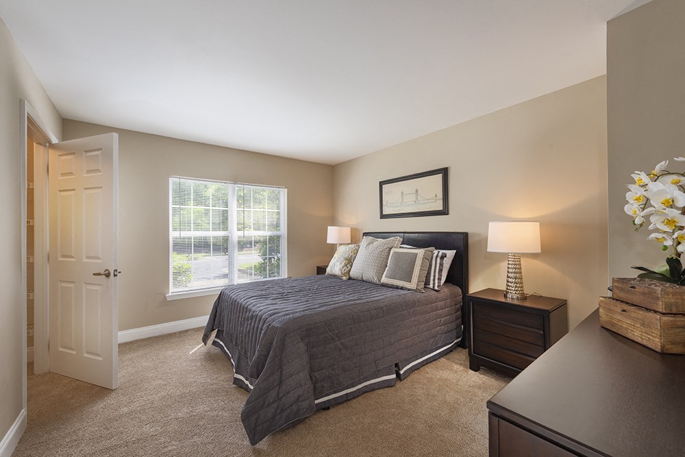 A bedroom with a bed, nightstand, and a window.