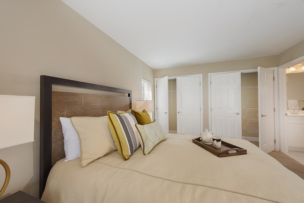 A bedroom with a large bed and a tray of cream colored flowers on the bed.