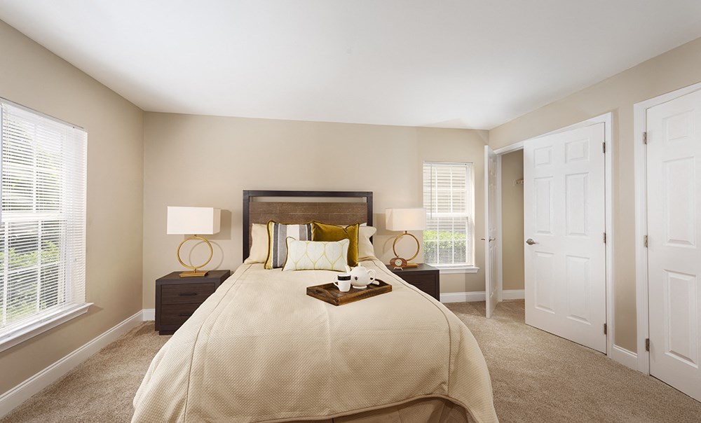 A bedroom with a large bed and a window with blinds.