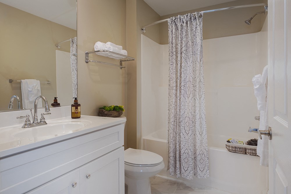 A white bathroom with a toilet, sink, and shower.