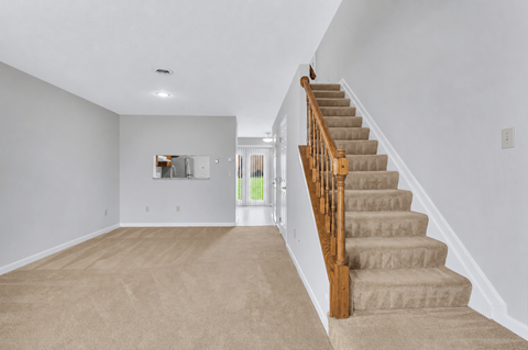 A staircase with a wooden handrail leads up to a second floor.