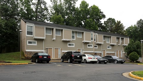 an apartment building with cars parked in a parking lot