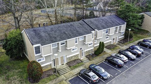 an aerial view of a house with cars parked in a parking lot
