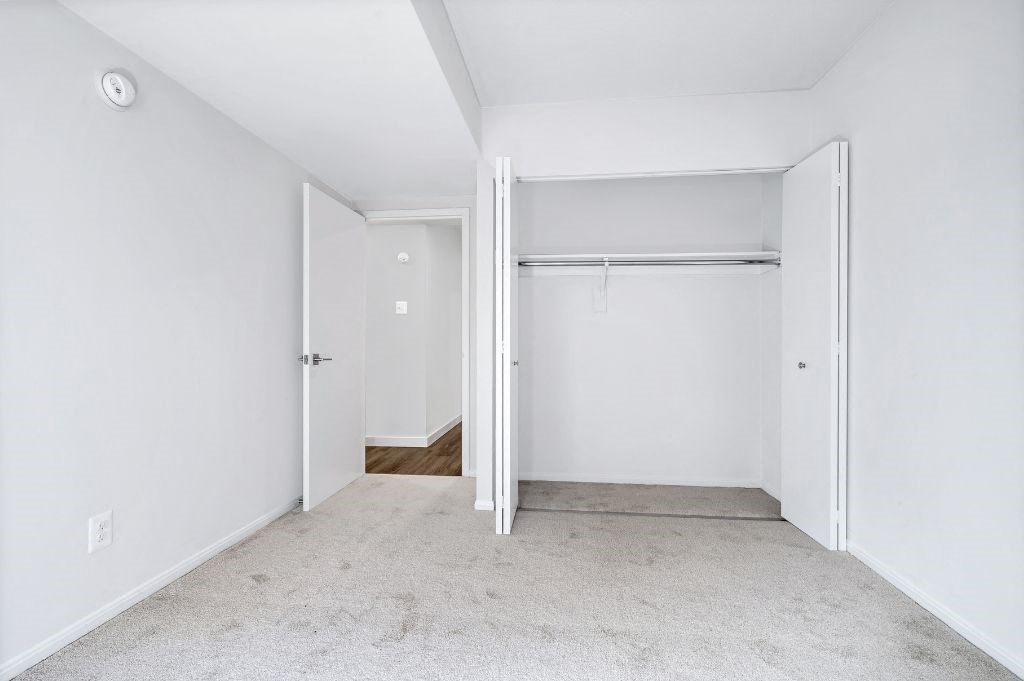 an empty bedroom with white walls and a closet