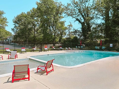 a swimming pool with red chairs around it