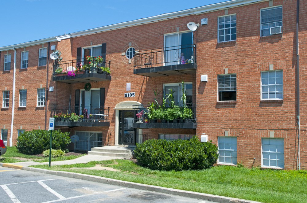 a red brick apartment building with balconies and grass