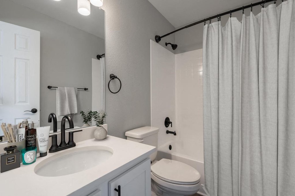 A bathroom with a white sink, toilet, and shower curtain.