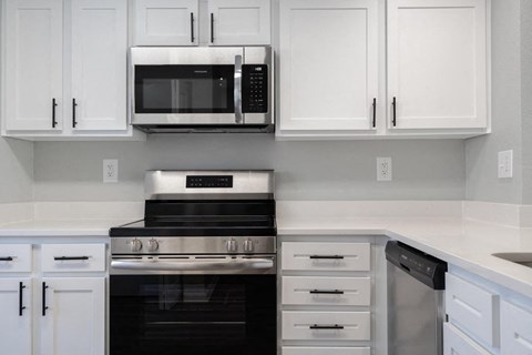 A modern kitchen with white cabinets and black appliances.