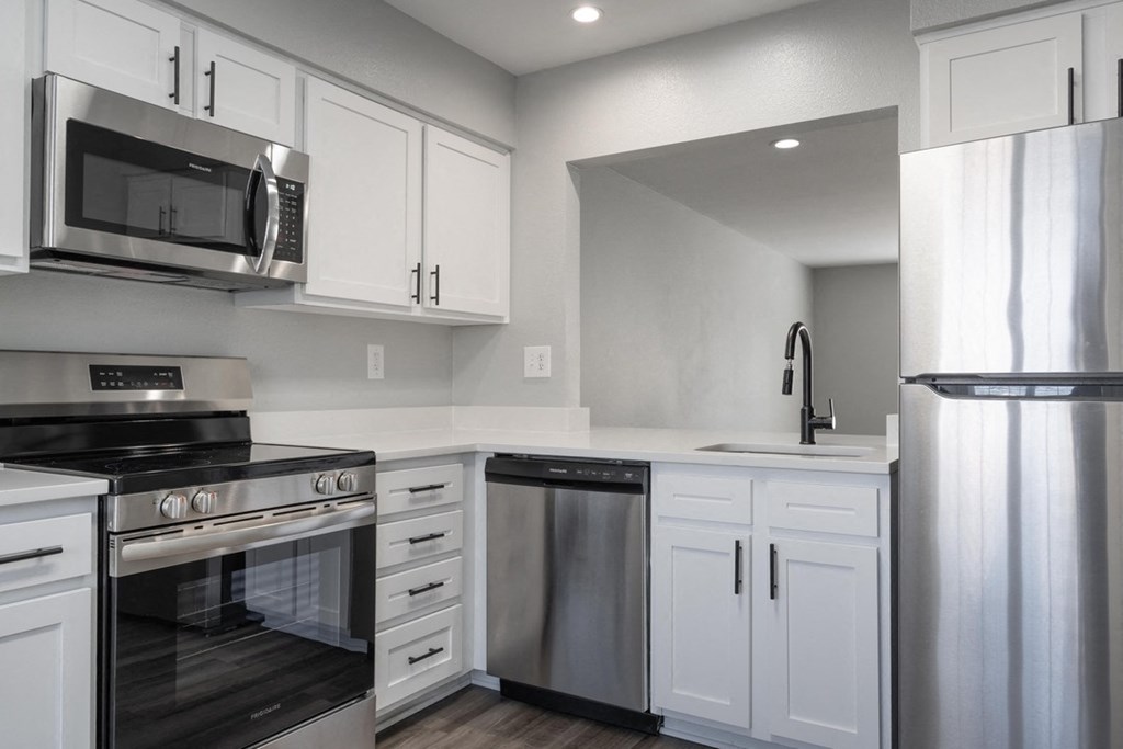 A modern kitchen with white cabinets and stainless steel appliances.